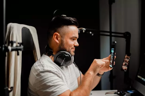 Man with headphones, recording a video on his phone